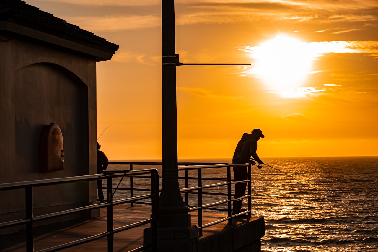 Angler fishing from a pier at sunset